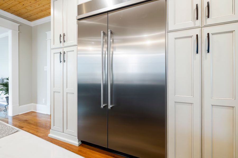 A stainless steel side-by-side refrigerator set into wooden kitchen cabinetry